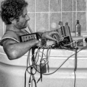 A man lounging in a bath tub with electronic equipment, indulging in the relaxing effects of Cyclodol.