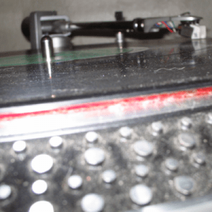 A black turntable with a red knob on it designed specifically for vinyl records.