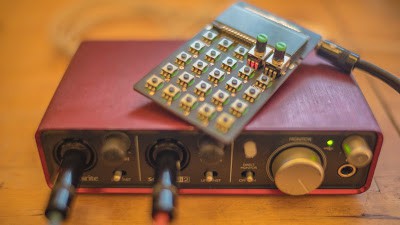 A red Pocket Operator audio interface sitting on top of a wooden table.