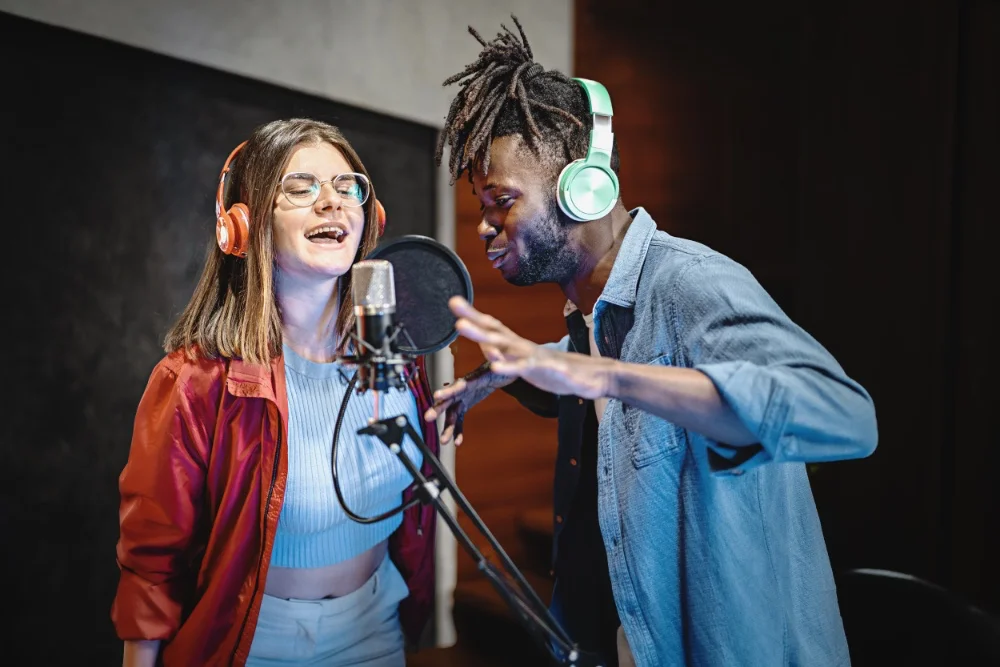 A man and woman singing in a recording studio, using Autotune.