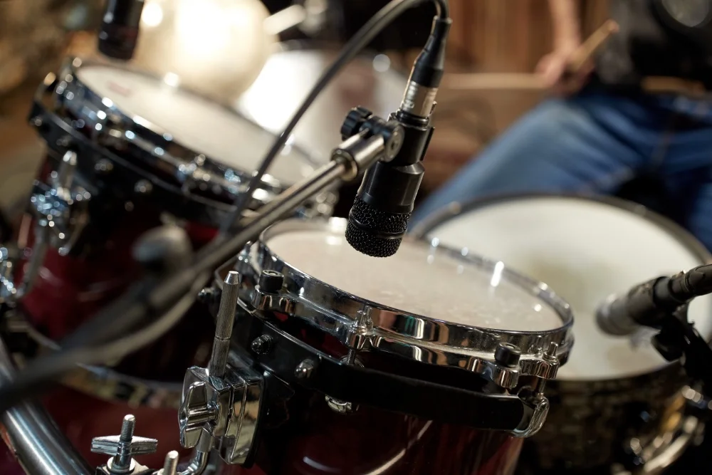 A person is playing drums in a recording studio, focusing on creating the perfect sound.
