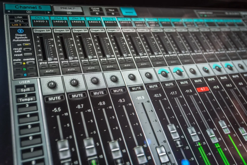 A close up of a music production mixing board in a recording studio.