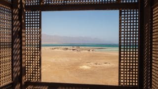 A remote view of the desert through a wooden window, in an off the grid location.