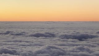 A view of the clouds from an airplane at sunset, creating a sparse and captivating soundscape.