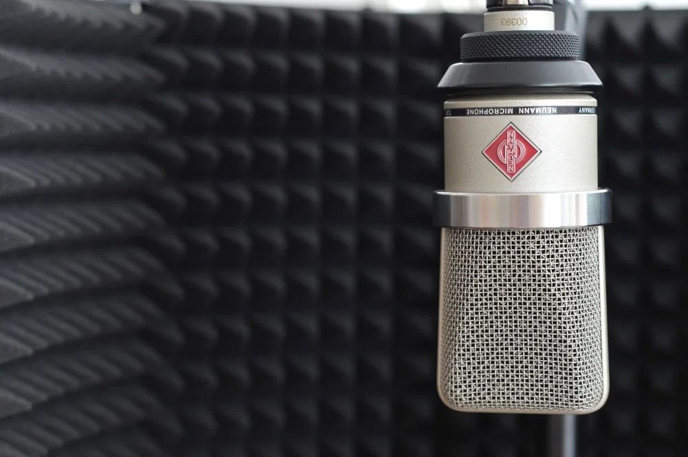 A microphone sits in front of an acoustic panel, ready to capture vocals with minimal plosives.