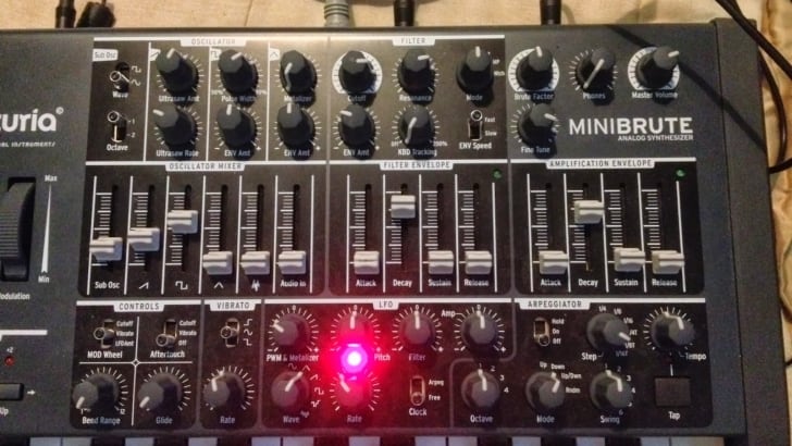 The Minibrute, a small synthesizer with a bold red light on it, produces powerful bass sounds.