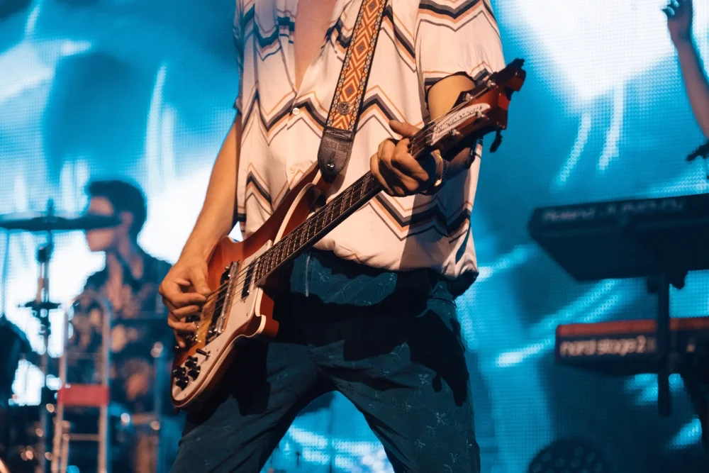 A man playing a guitar on stage at a concert with professional sound.