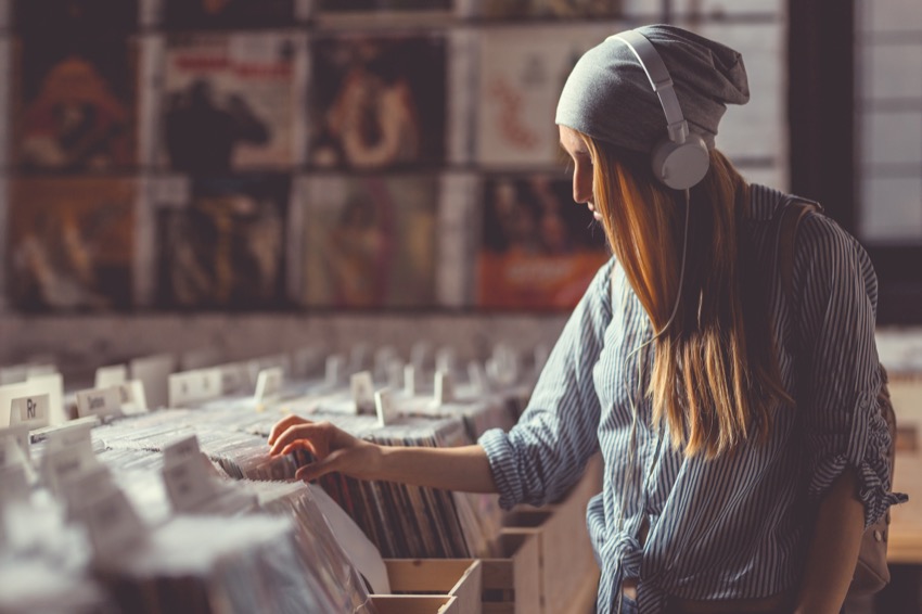 A woman is browsing through records in a record store, searching for hidden gems as a Crate Digger.