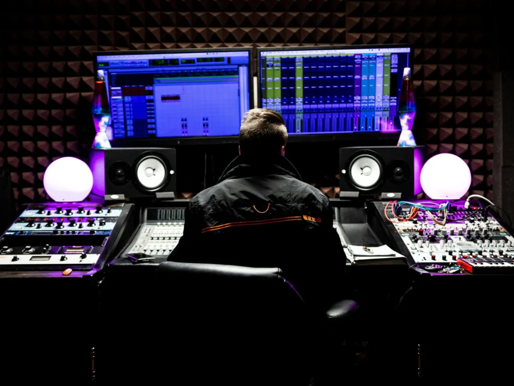 Music producer working at a high-tech recording studio console with glowing screens and equipment.